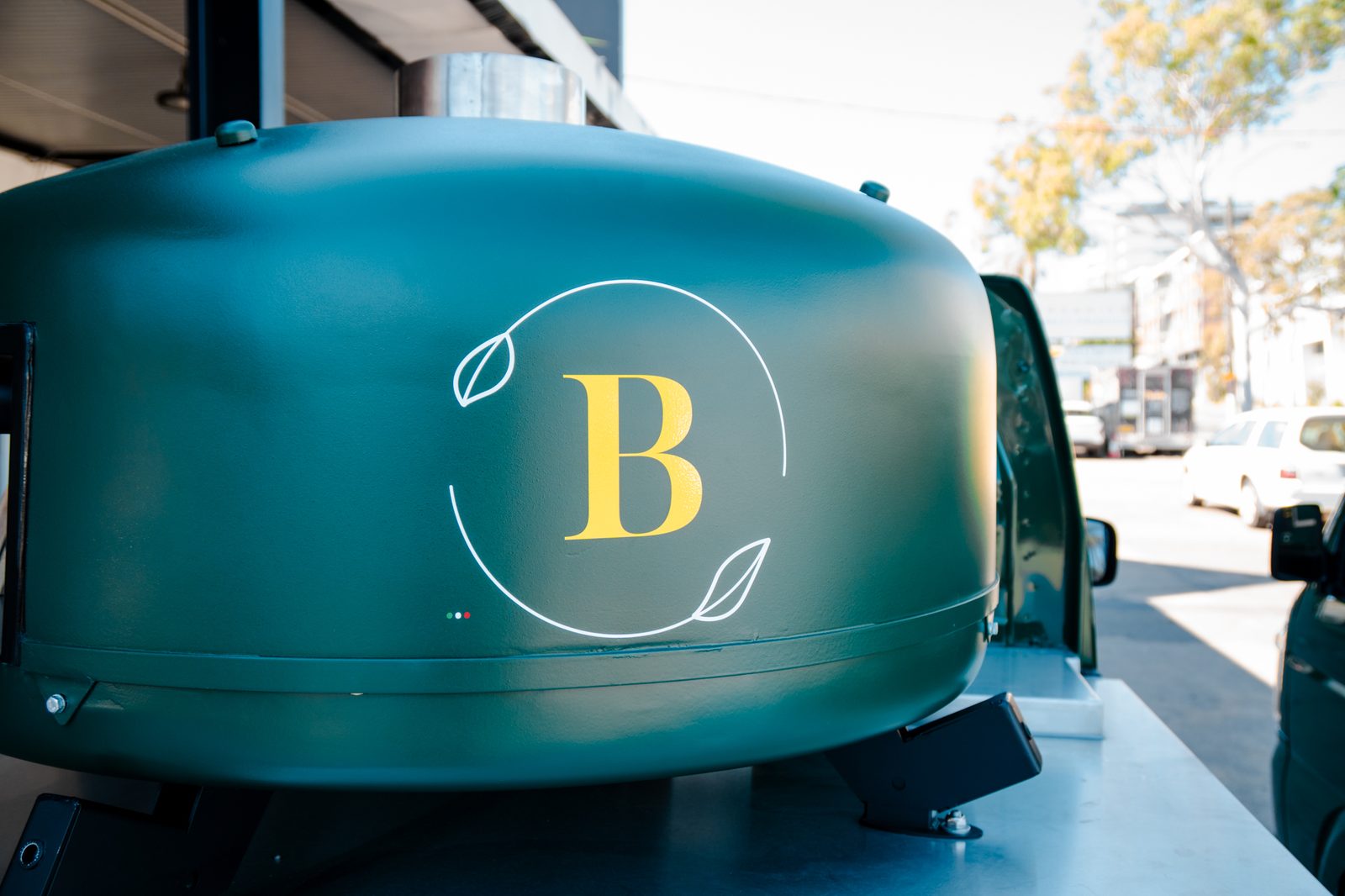 Basilico Pizza's green wood-fired oven with its gold B logo