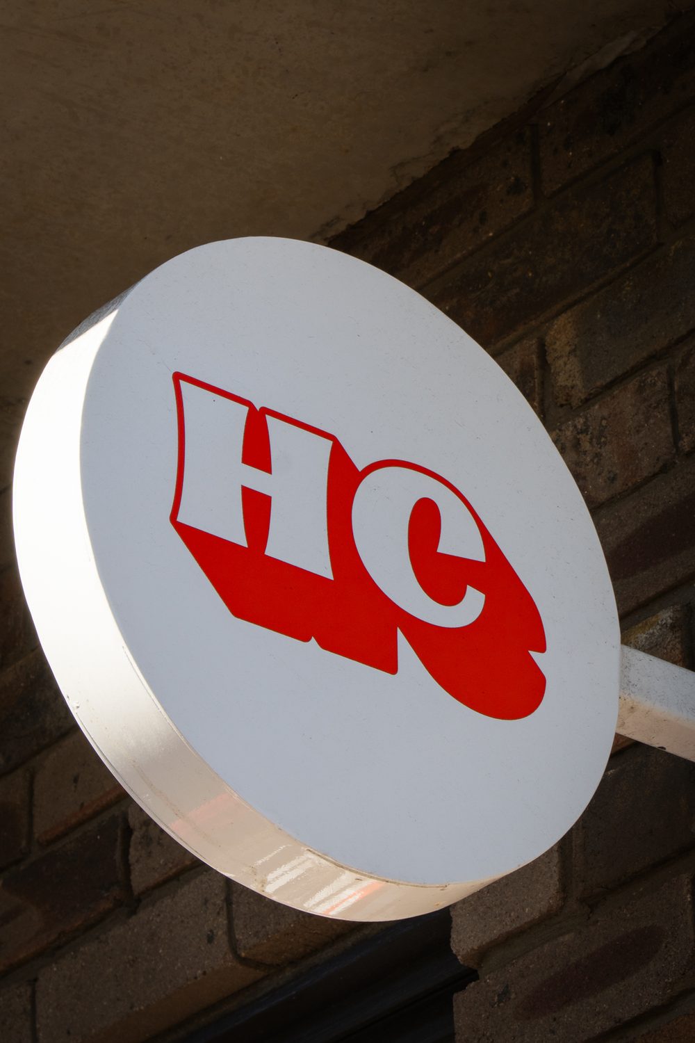 Round HC cafe sign mounted on a brick wall