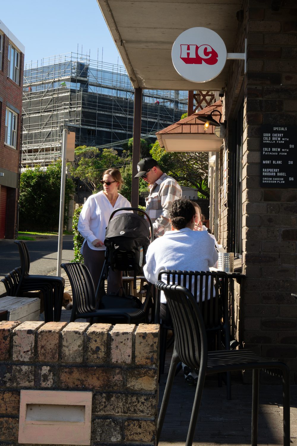 Customers at outdoor tables beneath the HC cafe sign