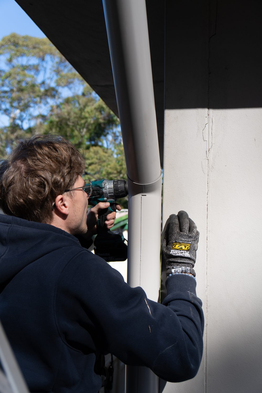North Shore Roofing & Gutters worker fixing a downpipe
